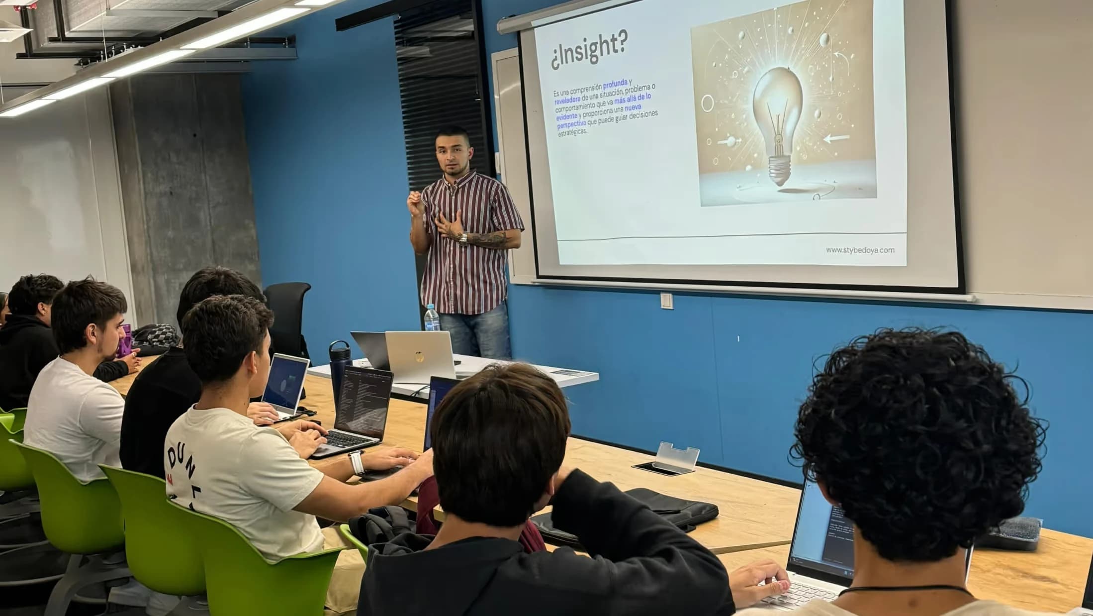 Styven giving a design talk to a room of students in front of a projected slide.