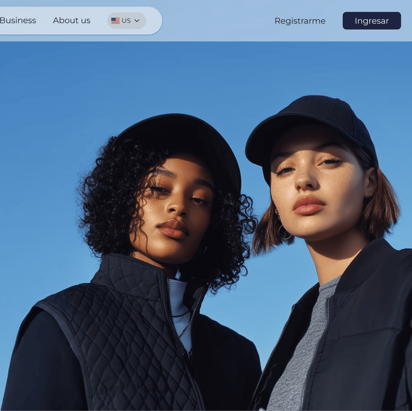 Website hero with two young women in caps and dark jackets photographed against a clear blue sky.